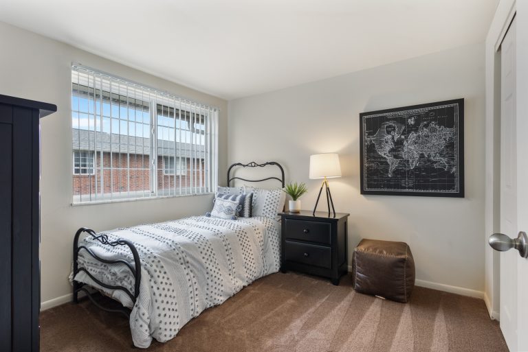 carpeted bedroom with a twin mattress bed pushed against wall