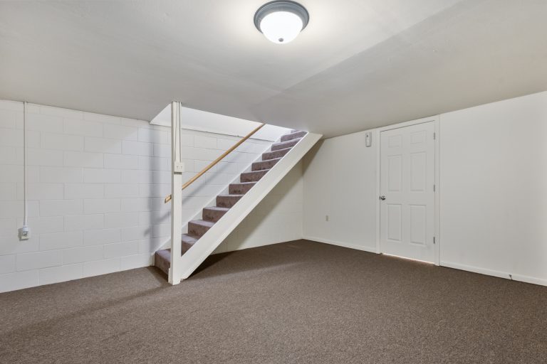 carpeted basement with a set of stairs in the center of the picture